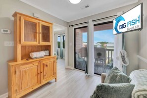A room with a wooden cabinet, a sliding glass door to a balcony, a fan, and a sign for Big Fish Rentals. - 1BR, A Relaxing  Place to Stay  Near the the Beach (Myrtle Beach)