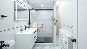A modern bathroom with a glass shower enclosure, a white vanity with a mirror, and a towel rack.