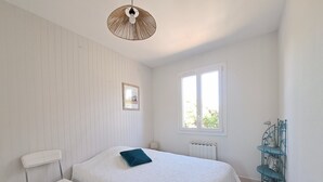 Een slaapkamer met een bed, een stoel, een raam en een radiator.