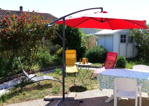 A patio with a red umbrella, two chairs, a table, and a small garden area. - Bungalow with a garden and forest, 50 m from the port of Meschers, Gironde (Meschers-sur-Gironde)
