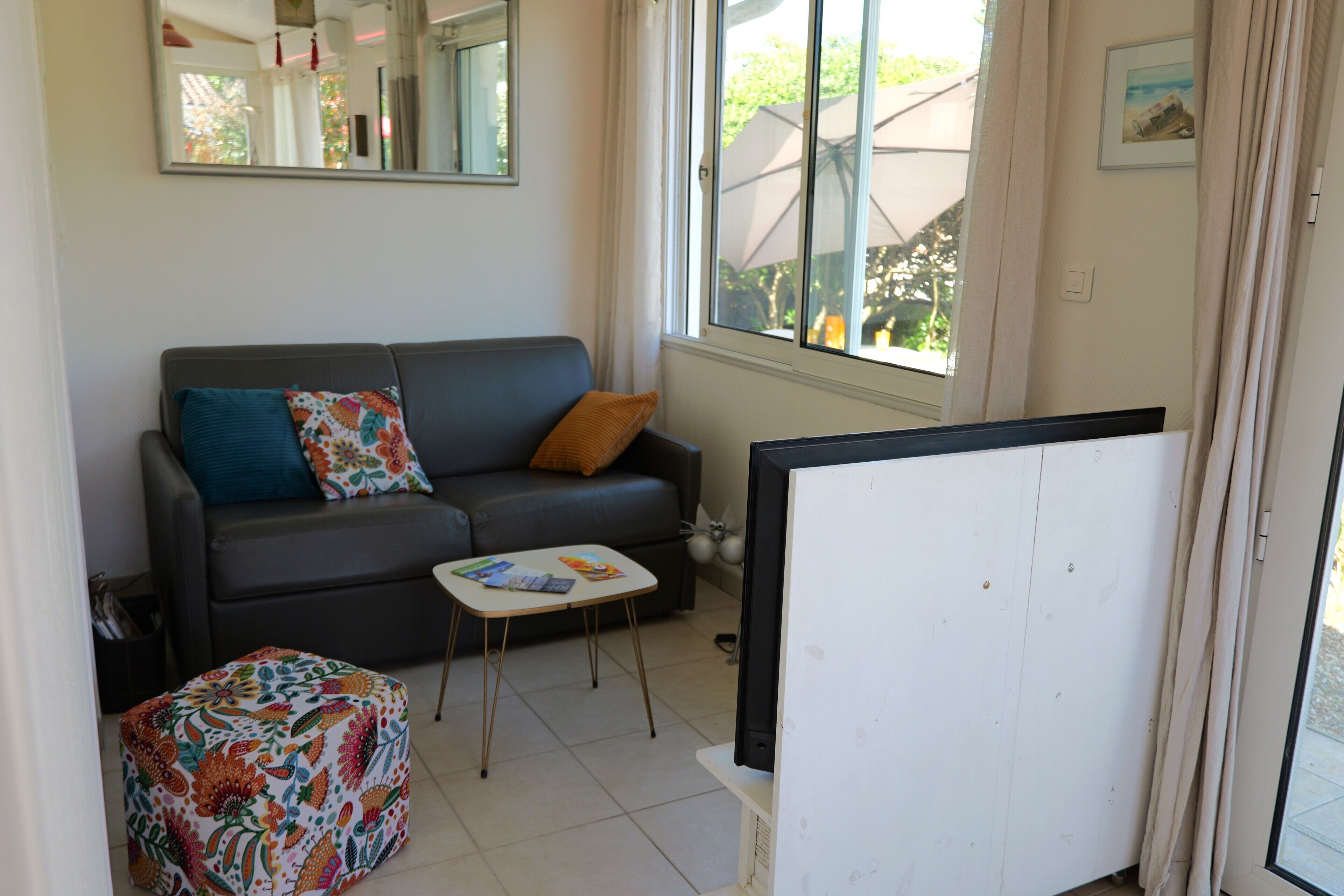 A living room with a sofa, a small table, a television, and a window with curtains.