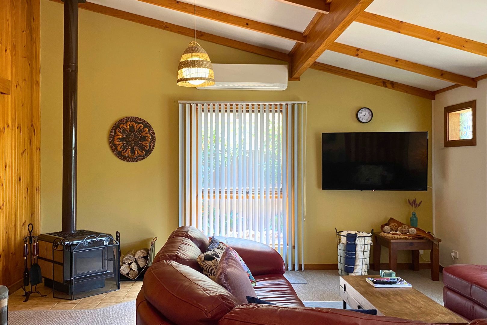 A living room with a sofa, a television, a fireplace, and a window with blinds.