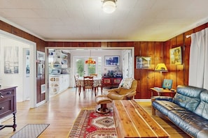 Un salon spacieux doté d’un plancher en bois, d’un canapé en cuir, d’une table basse en bois et d’un coin repas avec une table et des chaises.