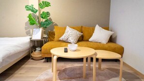 Une pièce comprenant un lit, un canapé, une petite table, une plante et une étagère fixée au mur.