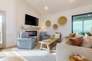Ein Wohnzimmer mit Flachbildfernseher, gestreiften Sesseln, einer Couch und dekorativen Tellern an der Wand.