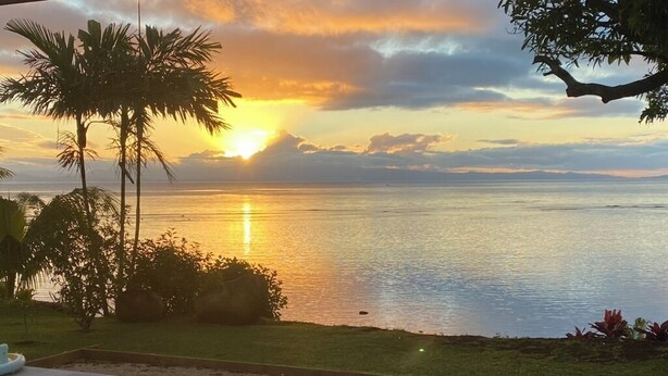 A pool with a view of the ocean at sunset.