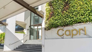 Une entrée moderne avec un escalier, un mur végétalisé et une enseigne indiquant « Capri ».