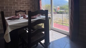 A dining area with a table set for two, a brick wall, and a sliding glass door leading to an outdoor view.