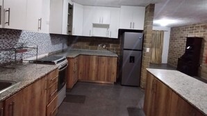 A kitchen with wooden cabinets, a stainless steel refrigerator, and a tiled backsplash.