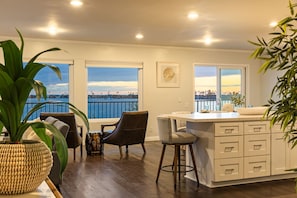 A modern kitchen with a view of the city, a bar area, and a seating space with a view. - Bay Breeze - Sand and Sun (San Diego)