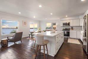 A modern kitchen with a large island, white cabinetry, and a view of the water. - Bay Breeze - Sand and Sun (San Diego)