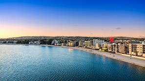 A coastal cityscape with a beachfront hotel, clear skies, and a calm sea. - Bay Breeze - Sand and Sun (San Diego)