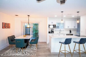 A modern kitchen with white cabinets, a central island, and pendant lighting. - Rock Waterfall Pool | FIFA Base | Bold Design (Wilton Manors)