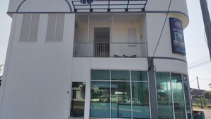 A two-story building with a balcony on the upper floor, large glass windows on the lower floor, and a sign reading 'INN HOTEL' above the entrance.