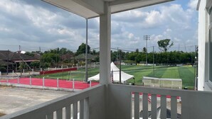 A covered outdoor area with a sports field, a red track, and a white tent.
