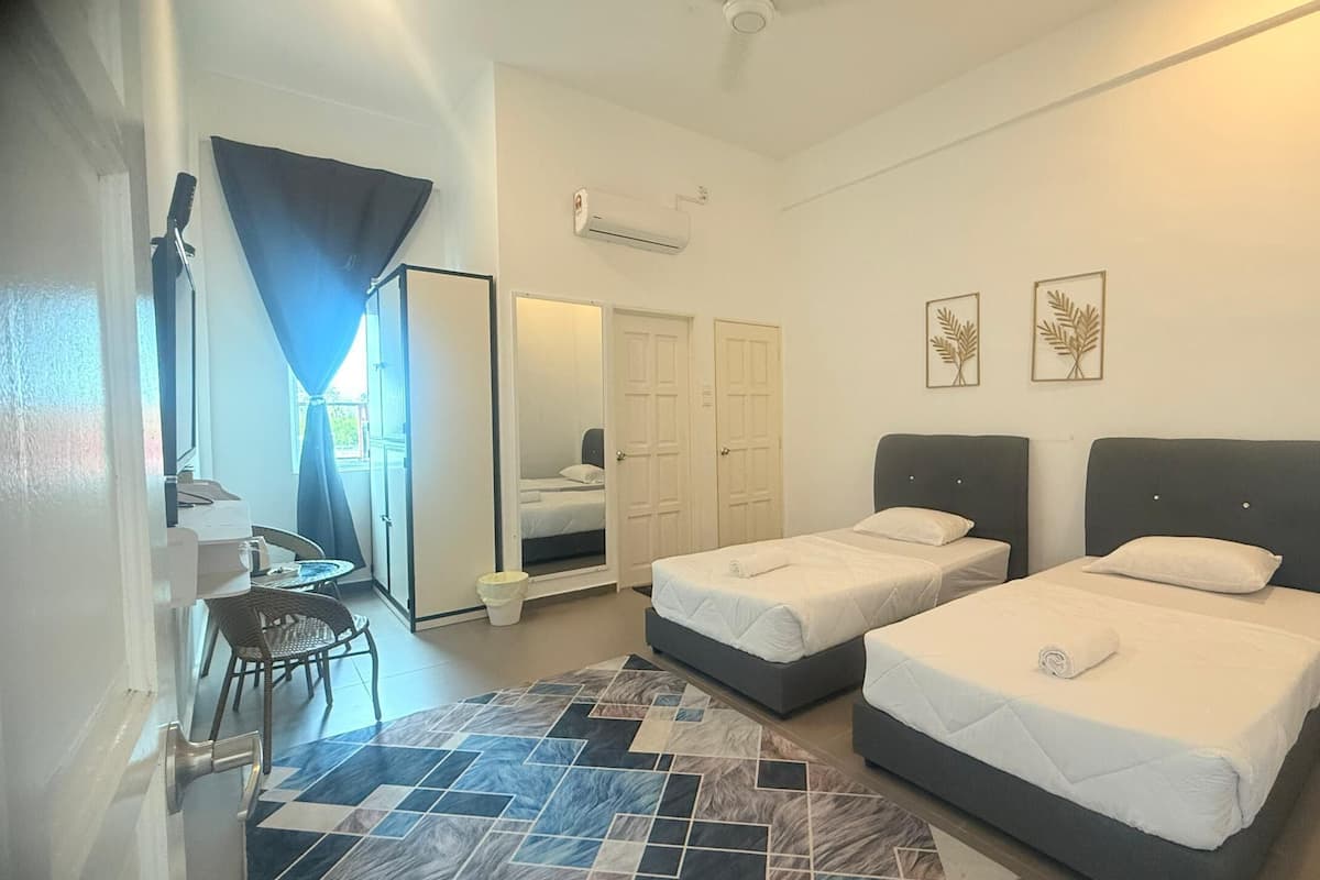 A hotel room with two beds, a desk, a chair, a patterned rug, and a large mirror.