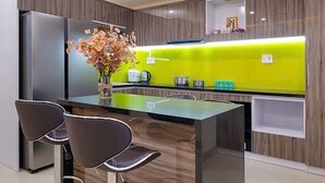 Een moderne keuken met een centraal eiland, barkrukken en een lichte spatwand.