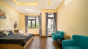 Een hotelkamer met een bed, twee stoelen, een klein tafeltje, een raam met gordijnen en een schilderij aan de muur.
