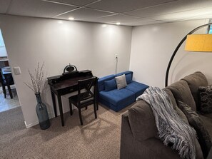 A living room with a blue sofa, a brown couch, a small desk with a chair, and a lamp. - Cozy 2 bedroom suite in downtown Kelowna BC (Kelowna)