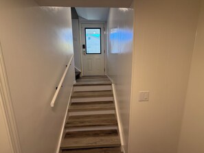 A staircase with wooden steps leading to a door with a window. - Cozy 2 bedroom suite in downtown Kelowna BC (Kelowna)