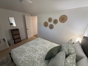 Ein Schlafzimmer mit Bett, Kissen, einem Schminktisch, einem Spiegel und Wandbildern.