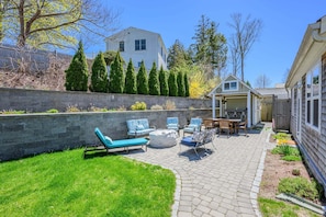A backyard with a stone patio, outdoor seating, a small shed, and a house in the background. - Cozy Getaway with Beach Pass & Sunroom (Osterville)