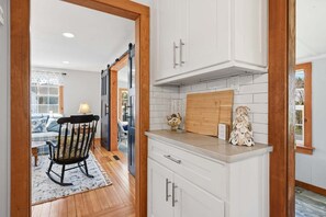 A kitchen with white cabinets, a wooden countertop, and a rustic decorative piece. - Cozy Getaway with Beach Pass & Sunroom (Osterville)