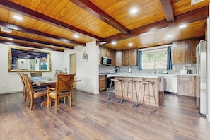 A kitchen with wooden cabinets, a bar area, and a dining table with chairs.