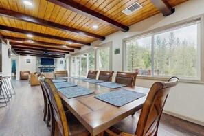 A conference room with a long table, wooden chairs, and large windows.