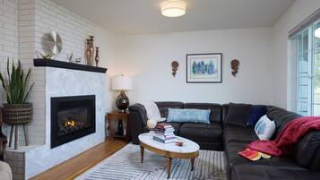 A living room with a fireplace, a sofa, a coffee table, and a bookshelf.