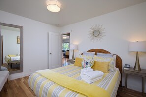 A hotel room with a bed, bedside tables, a mirror, and a sunburst wall decoration. - Sleep Inside Wine Country | 4BR, Fireplace (Milton-Freewater)