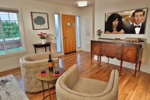 A living room with a sofa, a small table with a bottle and glass, a wooden cabinet, and a television.