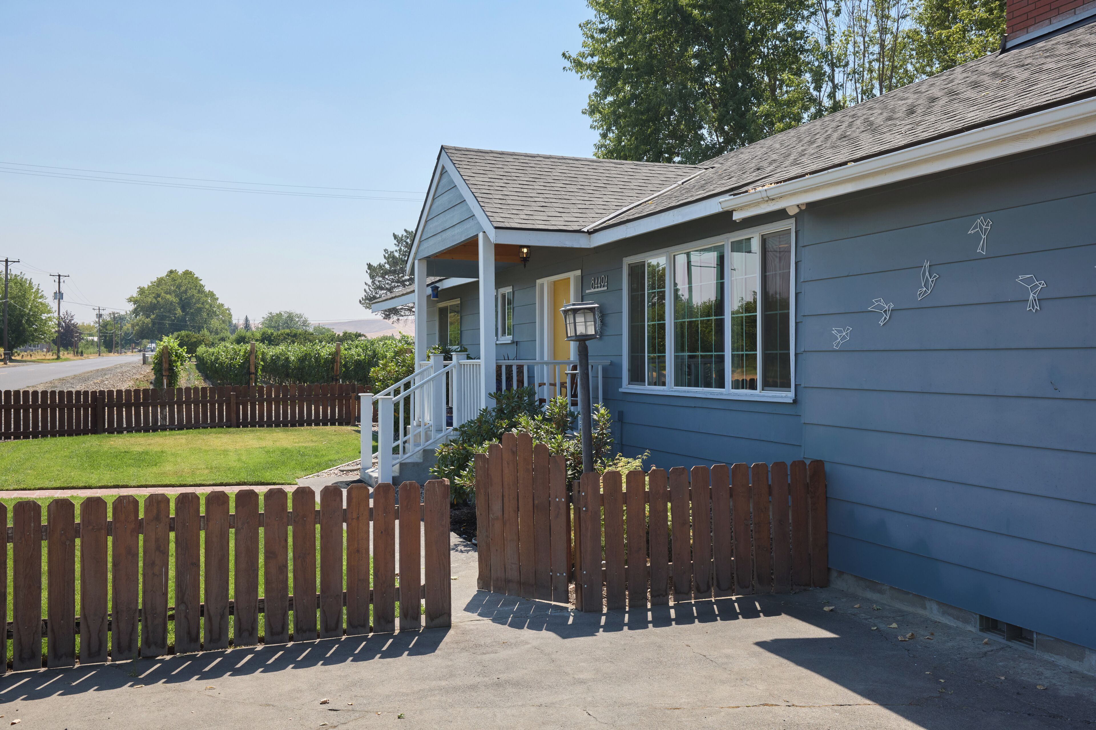 A residential property with a covered porch, a fenced yard, and a street view.