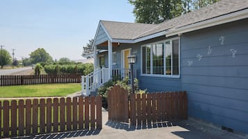 A residential property with a covered porch, a fenced yard, and a street view.