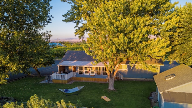 A house with a large tree, a deck, and a fenced yard. - Sleep Inside Wine Country | 4BR, Fireplace (Milton-Freewater)