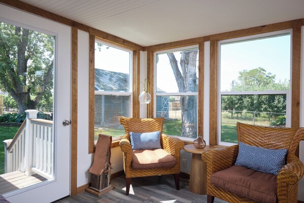 A sunroom with wicker furniture, large windows, and a view of the outdoors.