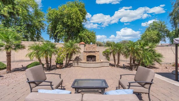 An outdoor patio with a stone fireplace, lounge chairs, and palm trees. - 5 Min to Stadium • Putting Green + BBQ (Glendale)