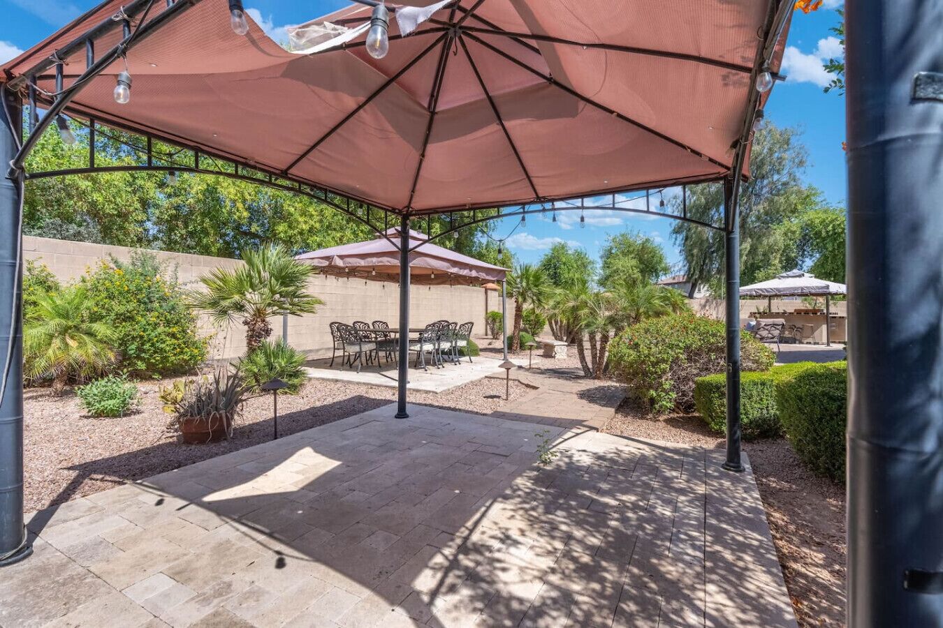 Ein überdachter Patio-Bereich mit Gartenmöbeln, einer Pergola und Blick auf die umliegende Landschaft.