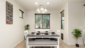 A dining area with a table set for four, a bench, and a chandelier. - 5 Min to Stadium • Putting Green + BBQ (Glendale)