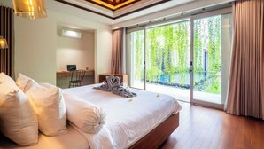 Camera d'albergo moderna con un letto grande, una scrivania e vista sul verde attraverso la porta scorrevole in vetro.