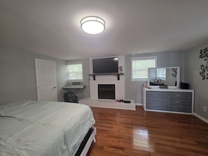 A bedroom with a bed, a fireplace, a television, and a desk.