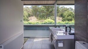 A modern bathroom with a large window, a white sink, and a toilet. - Thule Country Estate | Sleeps 12 | Private Lake, Pool & Farm | 45 mins Melbourne (Mount Macedon)