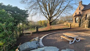 A picnic table in a gravel area with a brick building in the background. - Gîte with 9 rooms for 24 people (BRAINE LE COMTE)