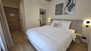 Une chambre à coucher comprenant un lit, des tables de chevet, une armoire et des œuvres d’art accrochées aux murs.