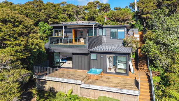 A modern two-story house with a balcony, a hot tub, and a deck. - Hekereua Heights - Spa & Ocean Views (Waiheke Island)