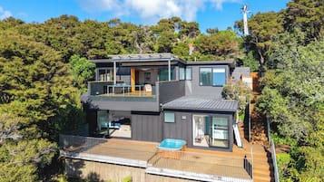 A modern two-story house with a balcony, a hot tub, and a deck.