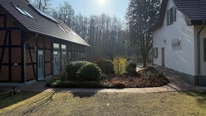 A courtyard with a brick building, a white building, and a garden area. - Stylishly furnished first floor apartment with garden view (Rheinsberg)