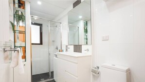 Une salle de bain moderne avec une douche à parois de verre, un lavabo blanc et des toilettes.
