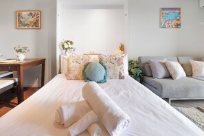 Ein Schlafzimmer mit einem Bett, einem Schlafsofa, einem Tisch und zwei Bildern an den Wänden.