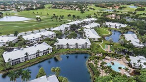 Ein Golfplatz mit mehreren Wasserflächen und einer Wohngegend mit weißen Gebäuden und Palmen.